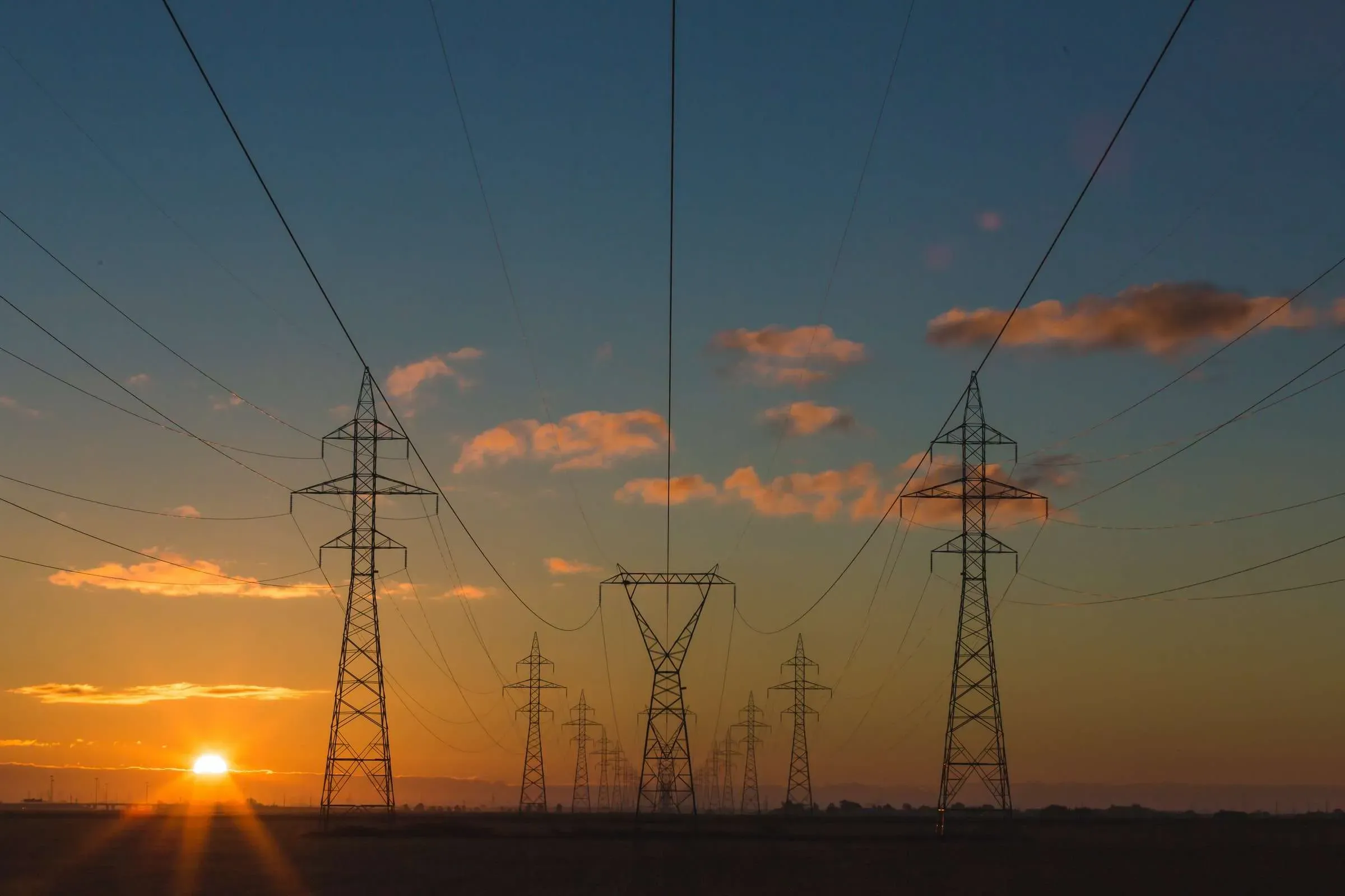 An image of powerlines vanishing into the sunset.